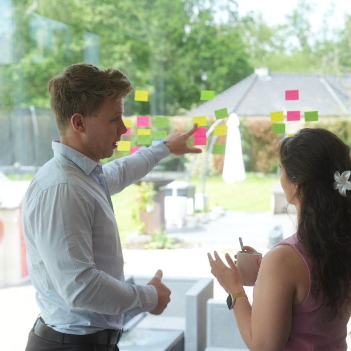 A Juwix designer points at post-its on a glass wall during a workshop